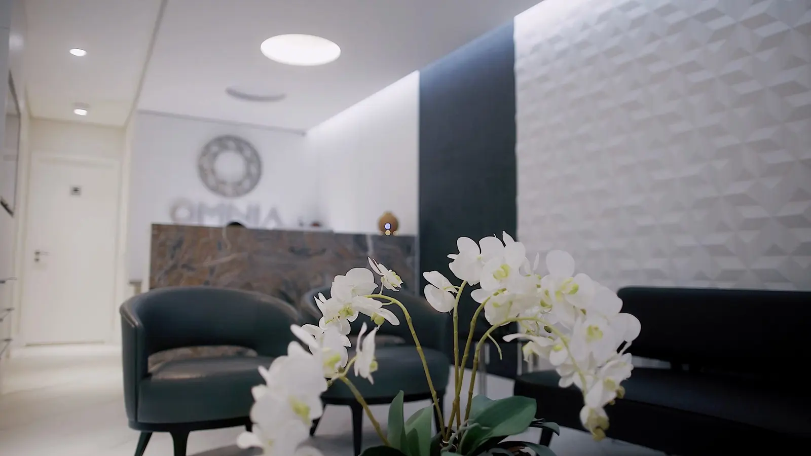 Sala de espera com poltronas e orquídeas brancas